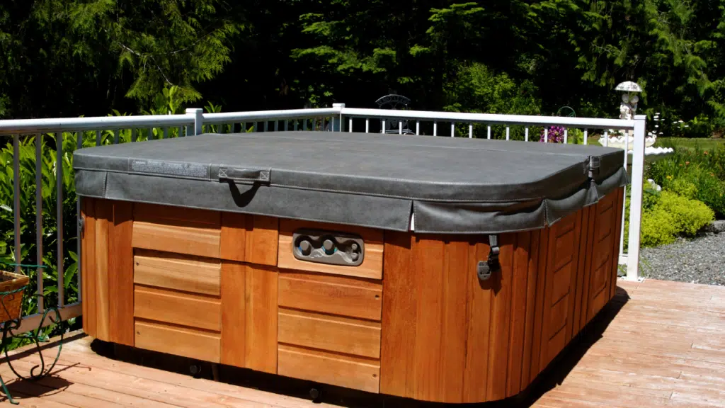 A wooden hot tub with a black cover.