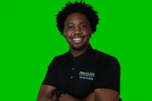 A man with his arms crossed in front of a green background.