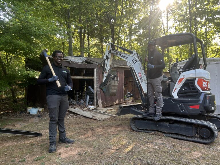 Two Pro Hauling employees removing a wooden shed in Greensboro, NC during a professional shed demolition and junk removal service